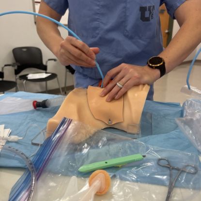 A person practices a surgical airway in the Center for Patient Simulation.